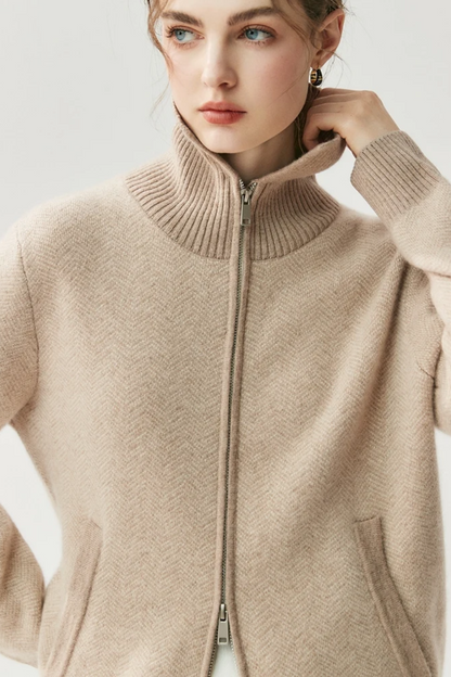 Close-up of a person wearing a camel zip-up sweater against a light background