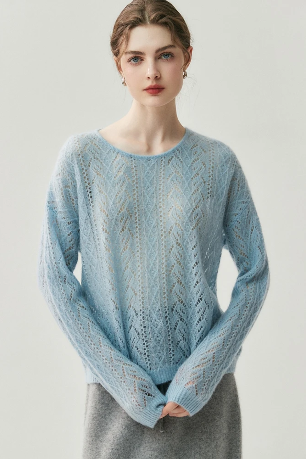 Woman wearing a light blue knitted sweater on a plain background