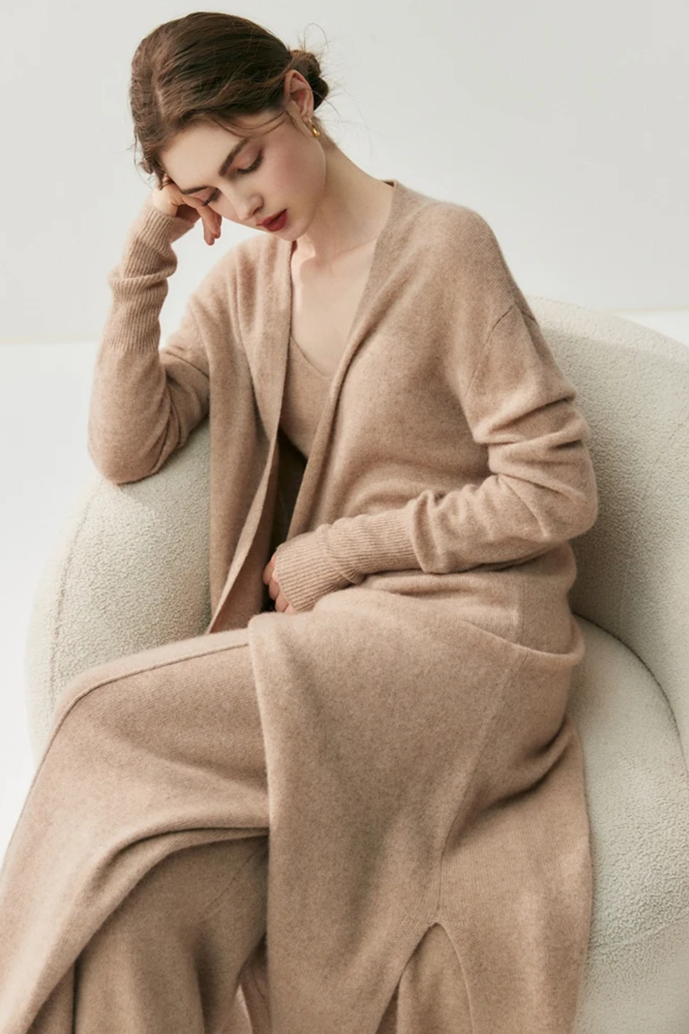 Woman wearing a camel sweater and pants set sitting down on a chair