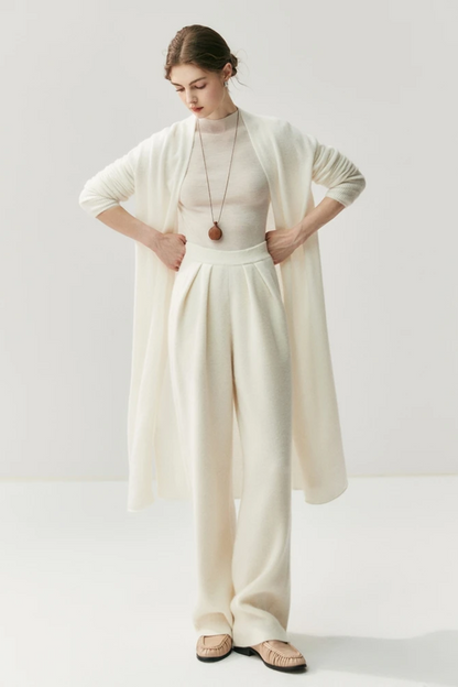 Woman wearing a white outfit with a ahite long cardigan on a white background