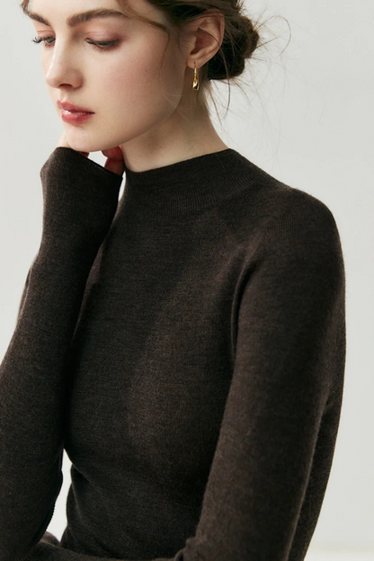 Woman wearing a dark brown sweater against a plain background
