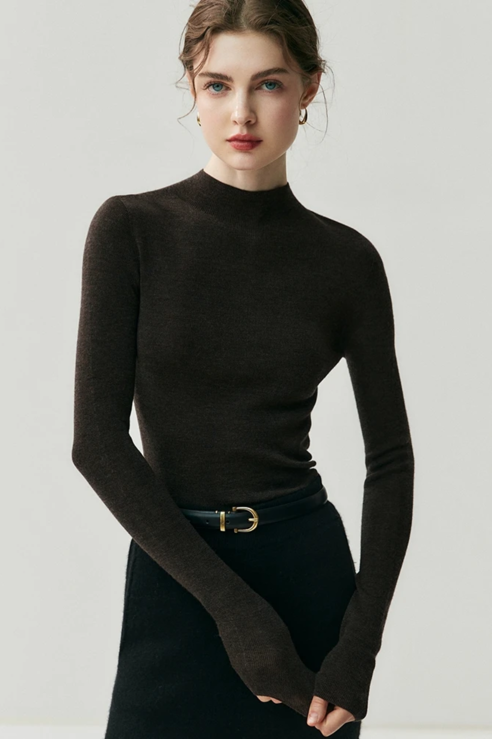 Woman wearing a dar turtleneck sweater against a white background brown