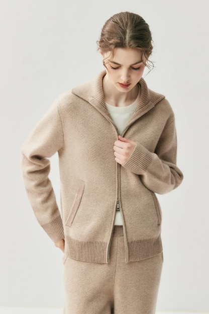 Close-up of a person wearing a camel zip-up sweater against a light background