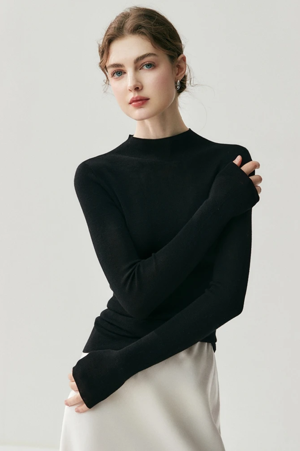Woman wearing a black turtleneck sweater against a light gray background