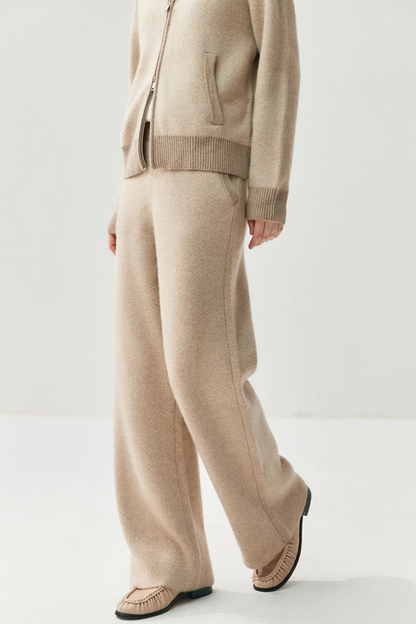 Person wearing a beige sweater and pants on a white background