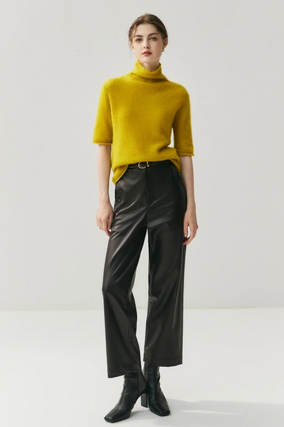 Person wearing a mustard yellow sweater and black pants on a white background