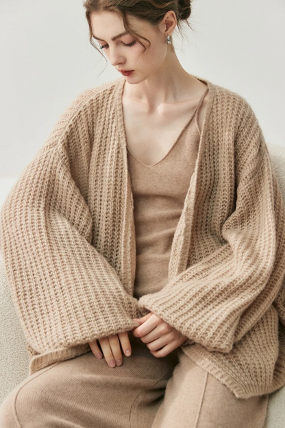 Woman wearing a camel knit cardigan and pants on a white background