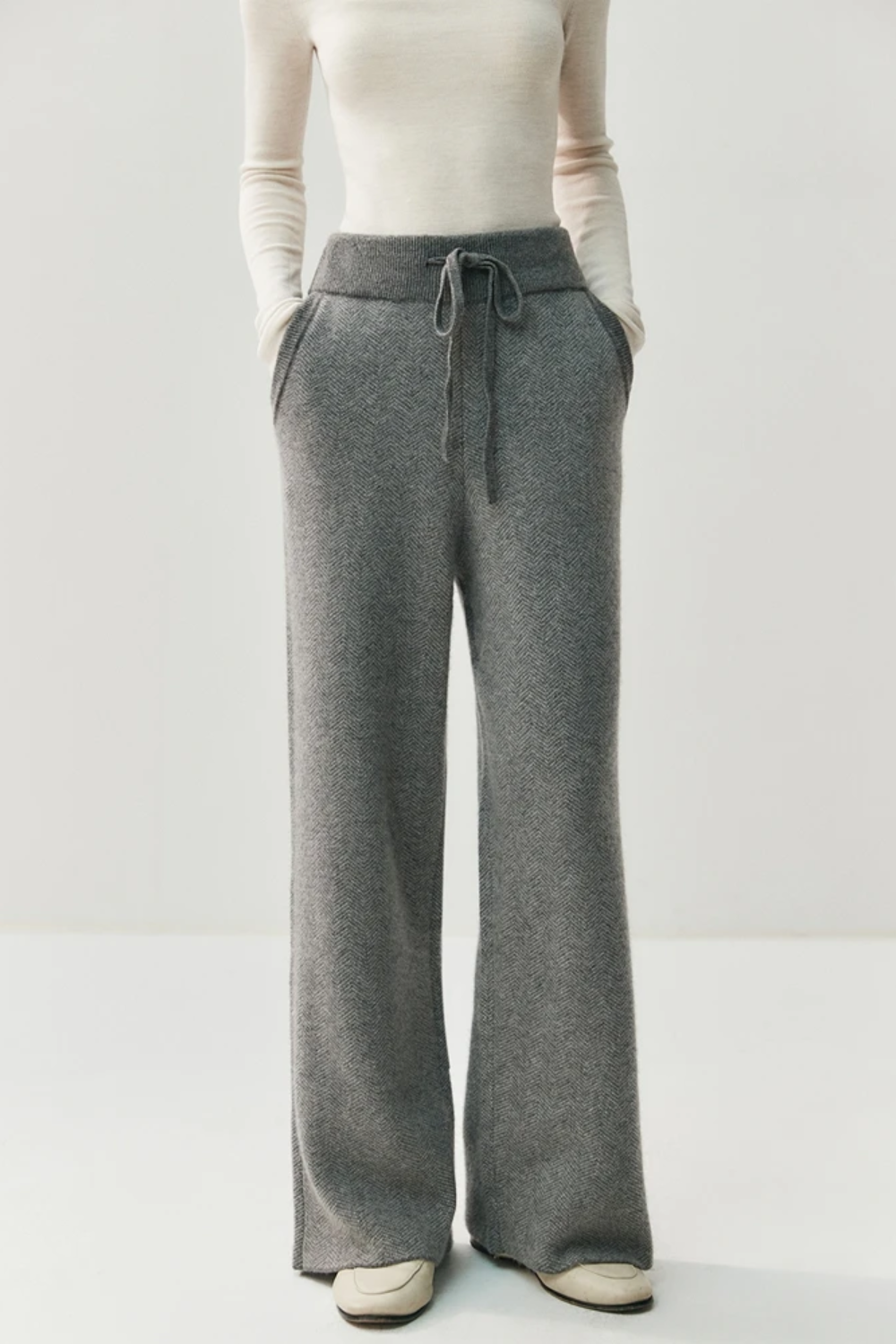 Person wearing gray drawstring pants on a white background