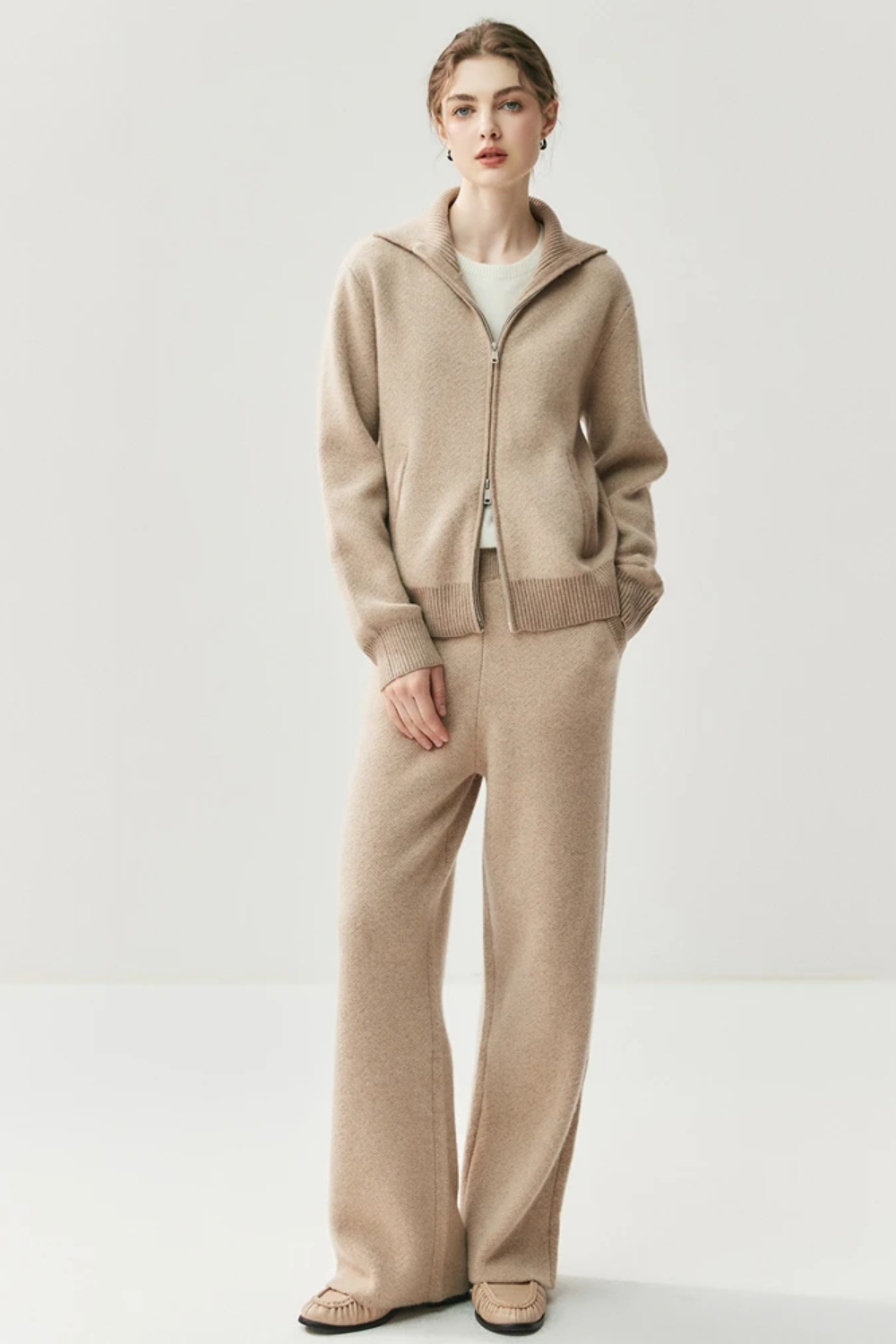 Woman wearing a camel cardigan and pants on a white background