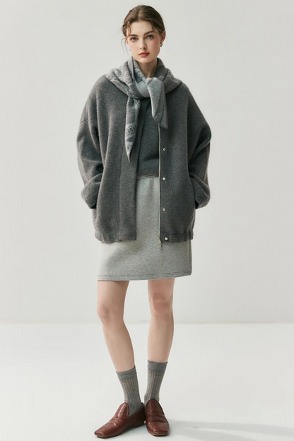 Woman wearing a gray cardigan with a scarf on a white background