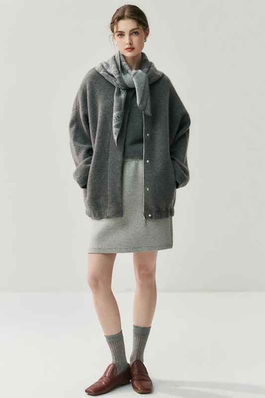 Woman wearing a gray cardigan with a scarf on a white background