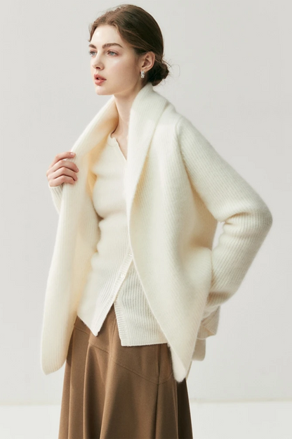 Woman wearing a white cardigan, beige blouse, brown skirt, and beige shoes on a white background