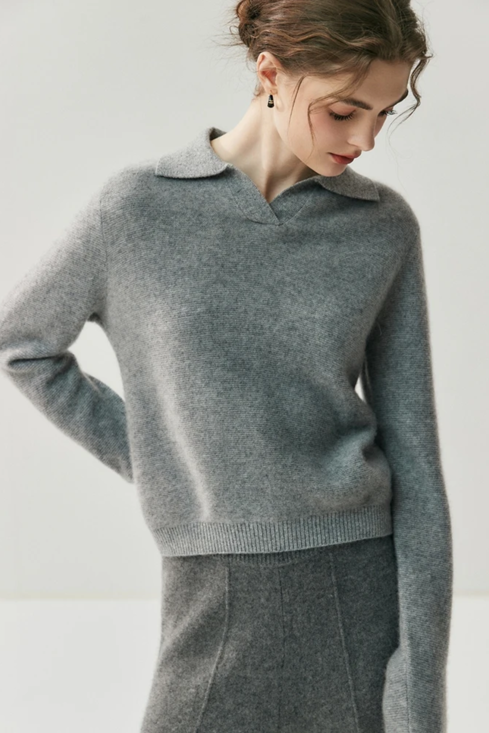 Woman wearing a gray sweater and pants against a white background