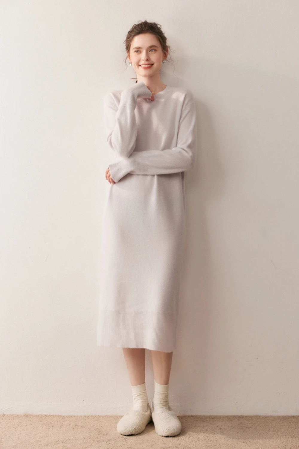 Woman wearing a long cream dress against a plain background.