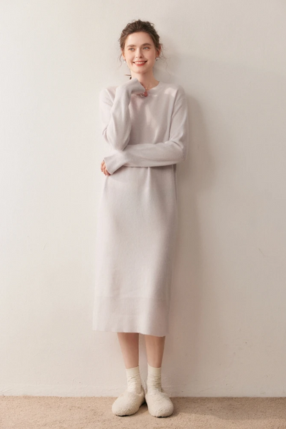 Woman wearing a long cream dress against a plain background.