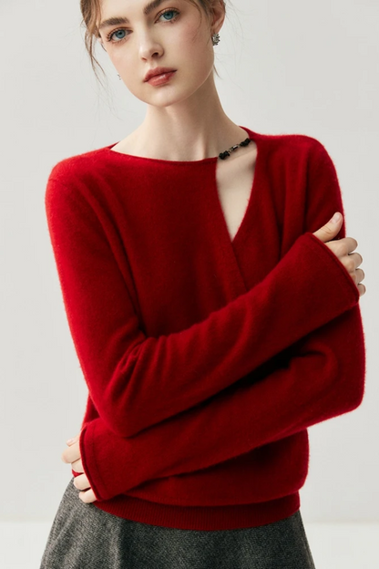 Woman wearing a red sweater with a cut out on the shoulder on a plain background