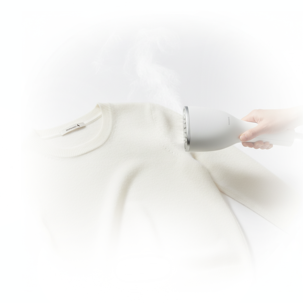 Person using a white garment steamer on a white shirt against a white background