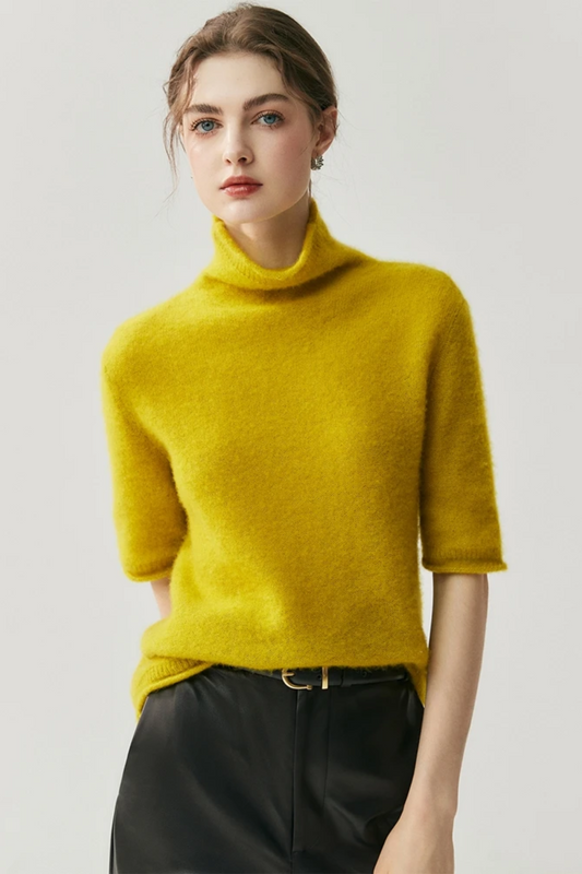 Person wearing a mustard yellow turtleneck sweater against a plain background