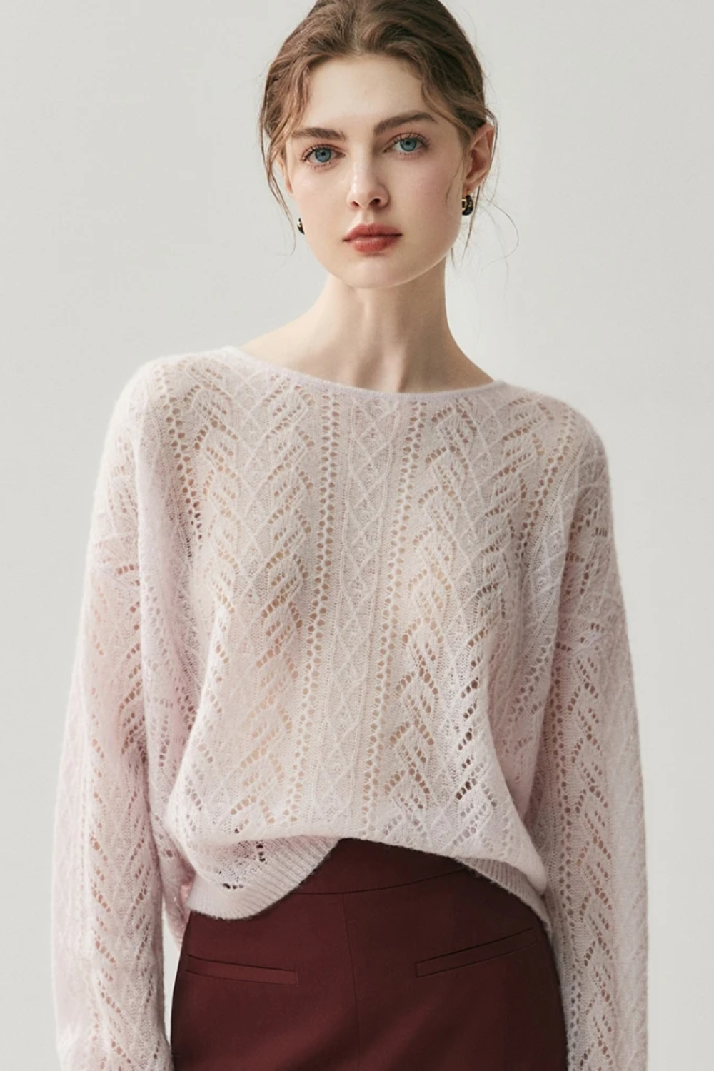 Woman wearing a light pink knitted sweater against a white background