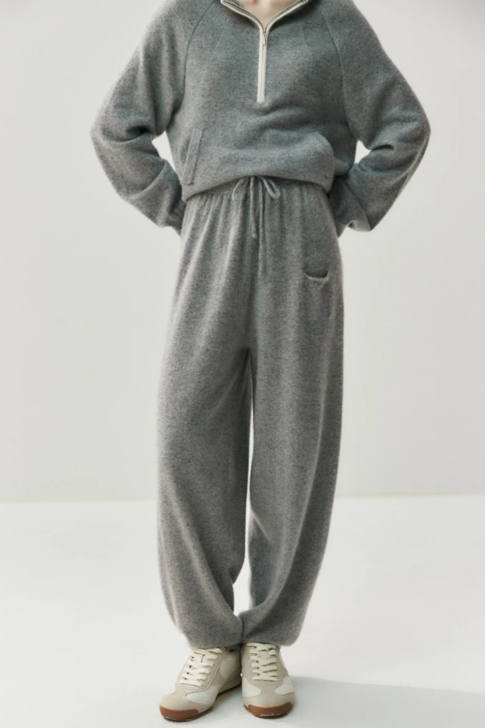 Person wearing a gray sweater and pants set on a white background