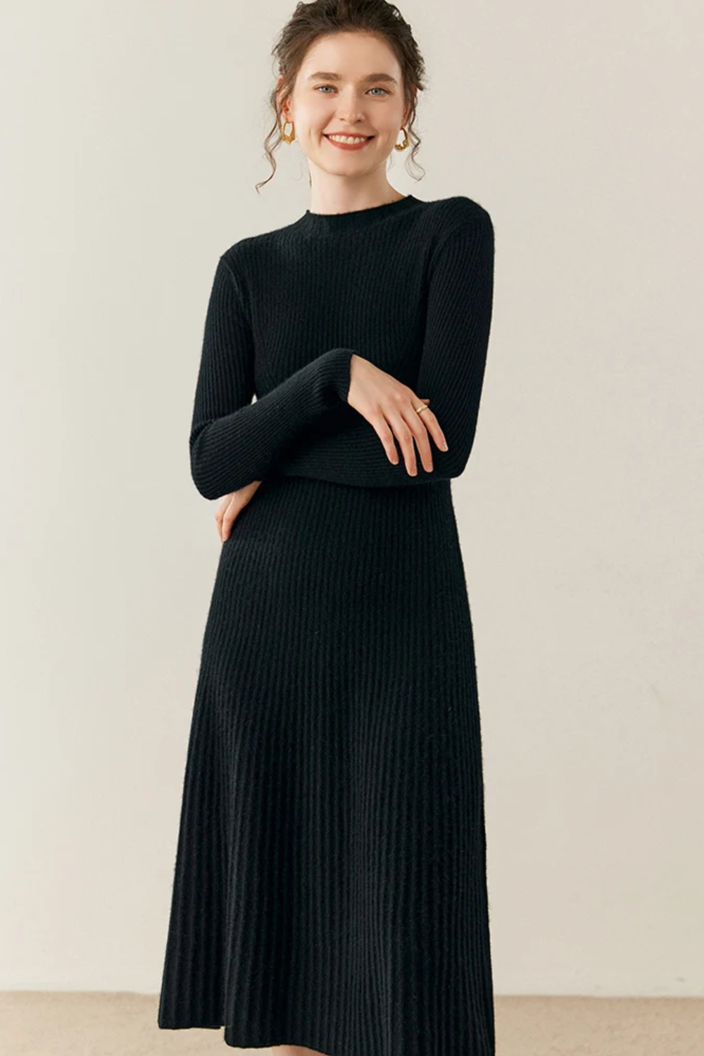 Woman wearing a black ribbed dress against a plain background