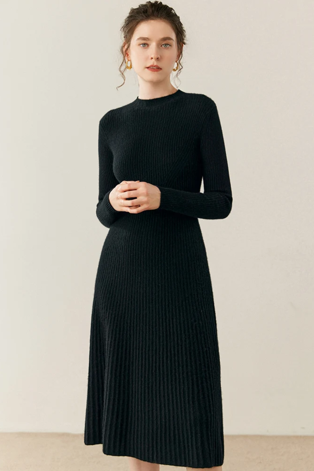 Woman wearing a black ribbed dress against a plain background
