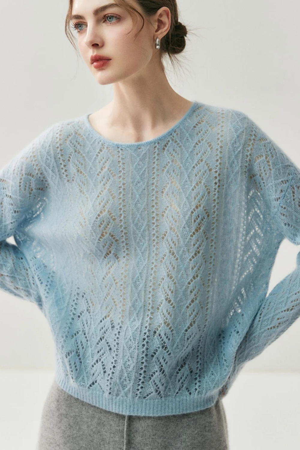 Woman wearing a light blue knitted sweater against a plain background