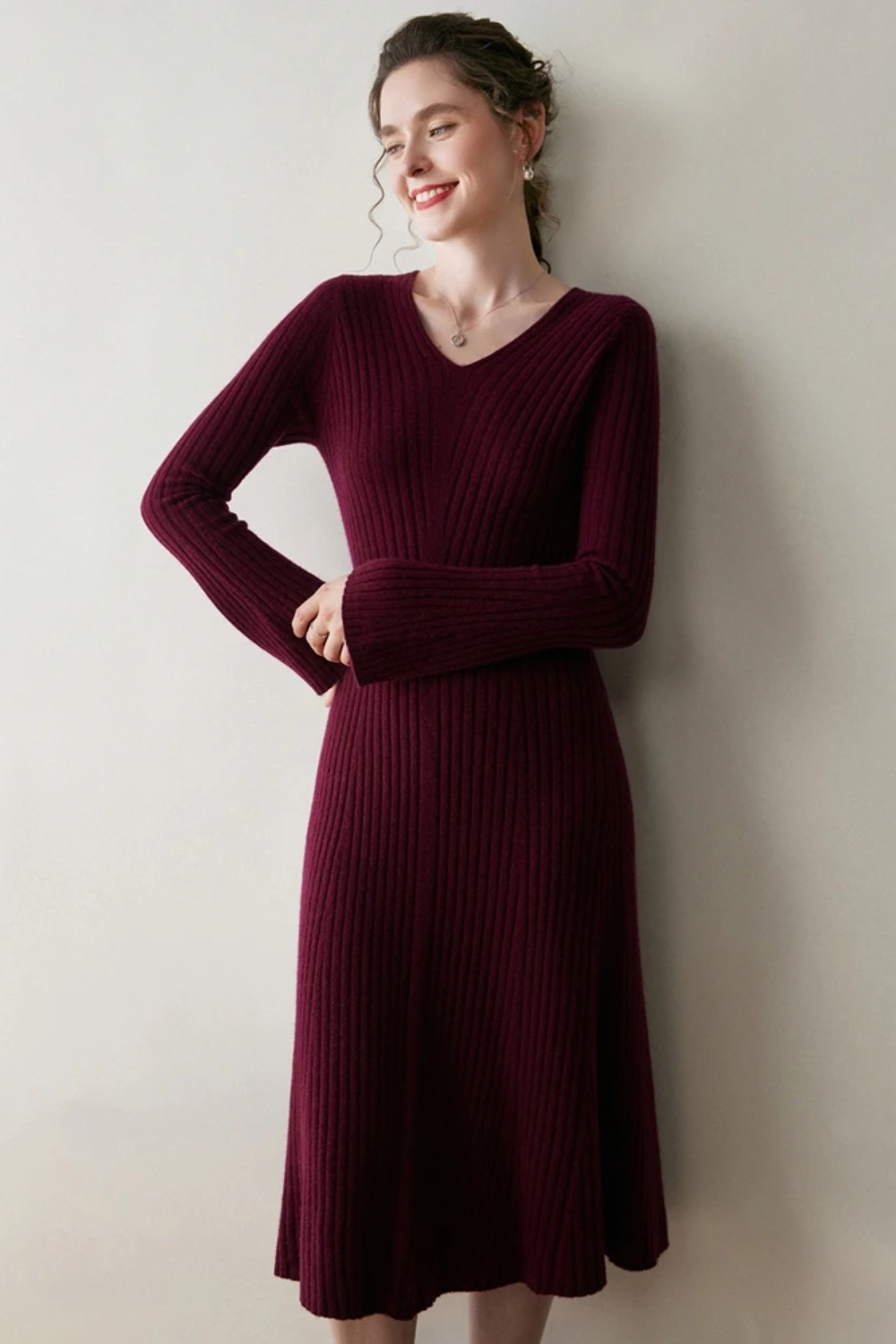 Woman wearing a burgundy ribbed dress against a plain background