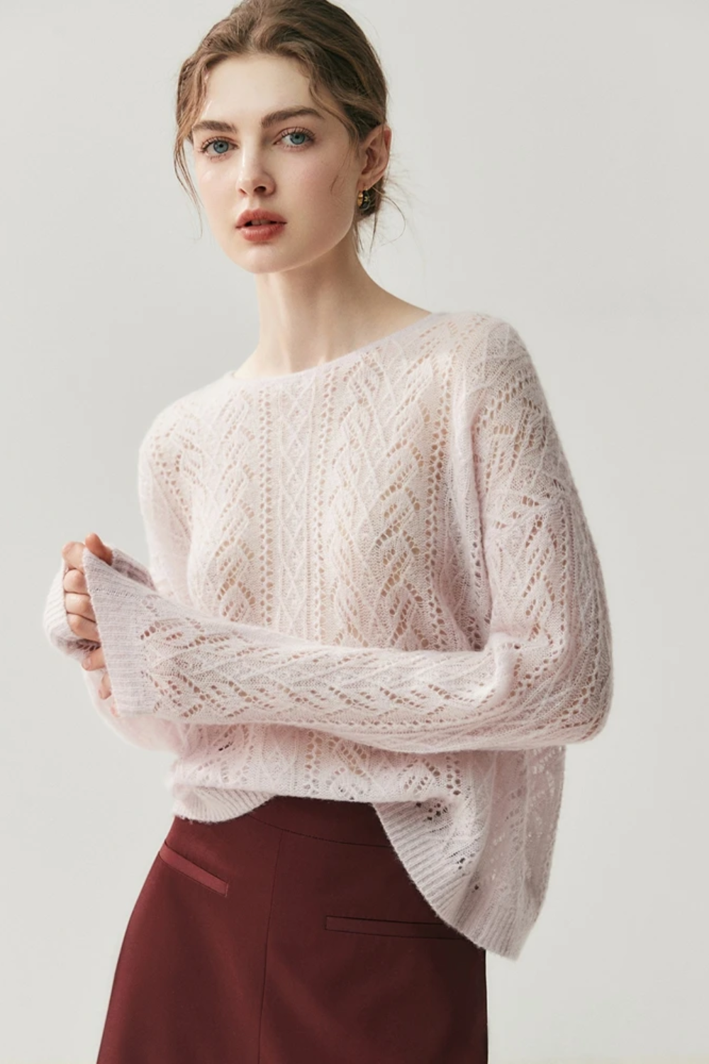 Woman wearing a light pink knitted sweater against a white background