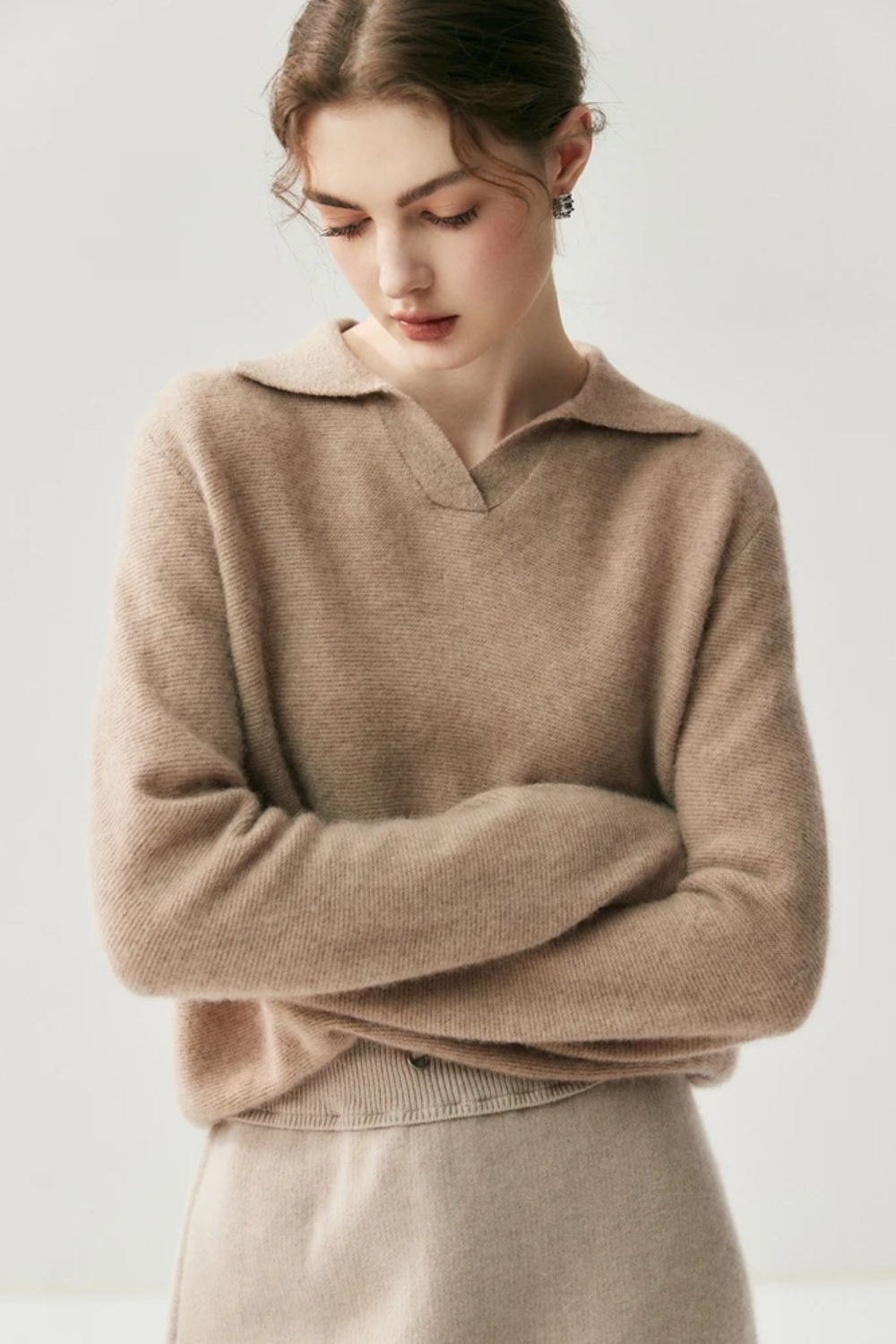 Woman wearing a camel coloured sweater against a plain background