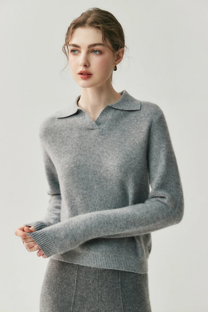 Woman wearing a gray collared sweater and pants against a white background